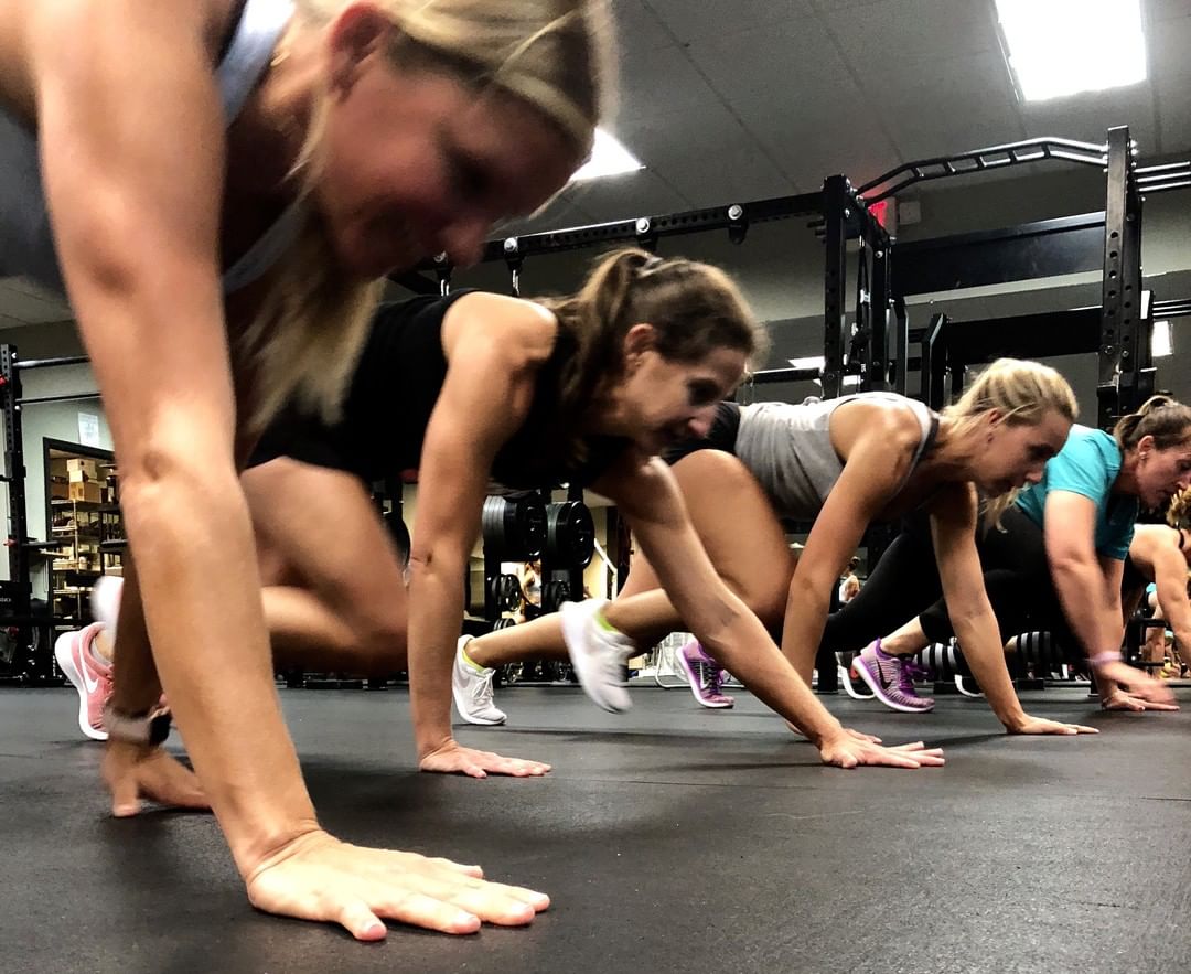 Members crawl through a floor drill during a group class.