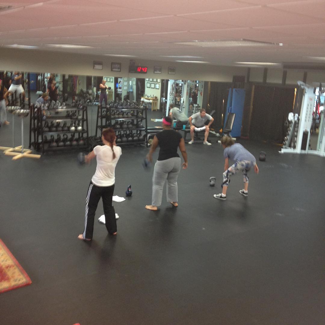 Members practice kettlebell swings in a group class.
