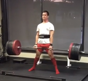 Standing tall at lockout in a lifting belt and knee-high socks.